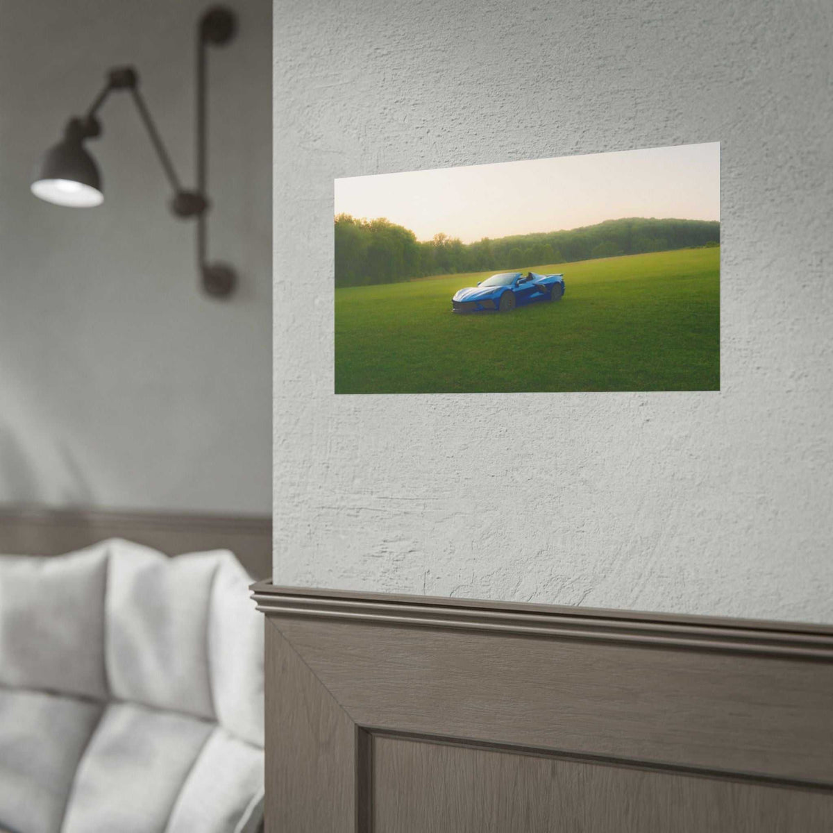C8 Corvette Stingray blue sports car in a green meadow with sunlit haze and distant tree line under a soft sky