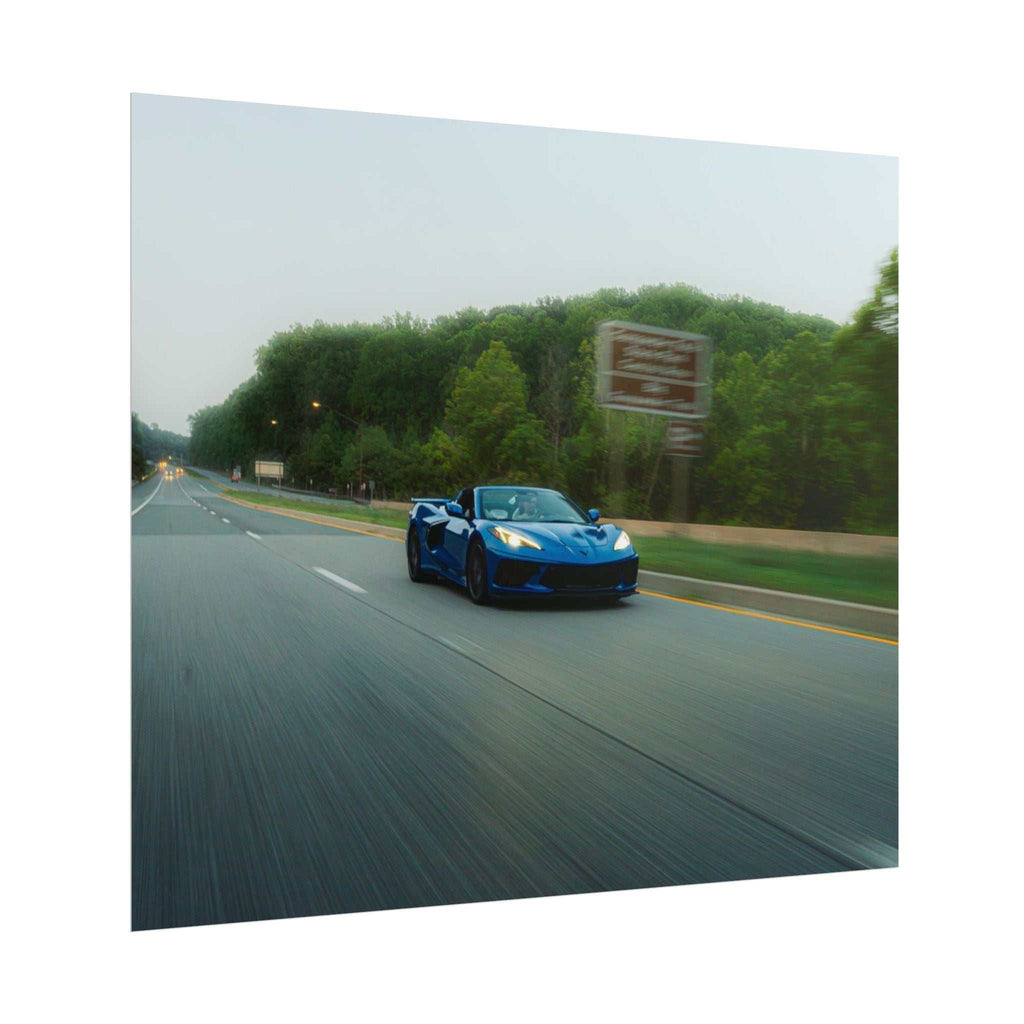 C8 Corvette Stingray in blue driving on a highway with motion blur and green trees in the background