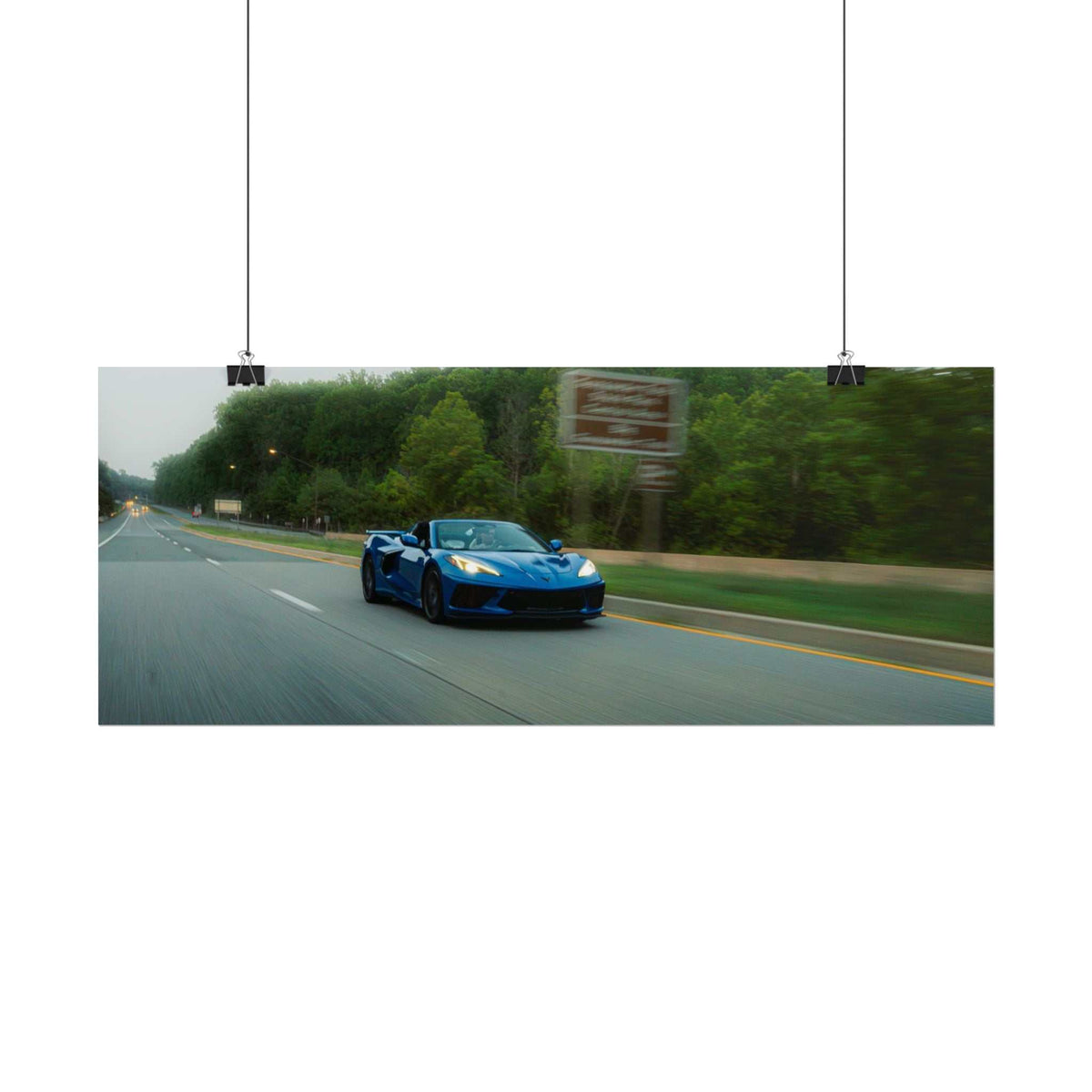 C8 Corvette Stingray blue sports car driving on a tree-lined highway with motion blur and crisp highlights
