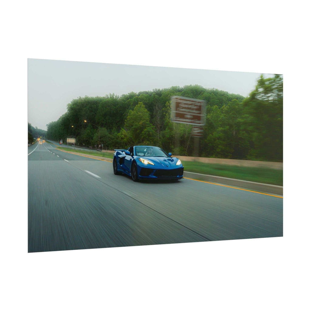 C8 Corvette Stingray blue sports car driving fast on a tree-lined highway with motion blur and clear sky