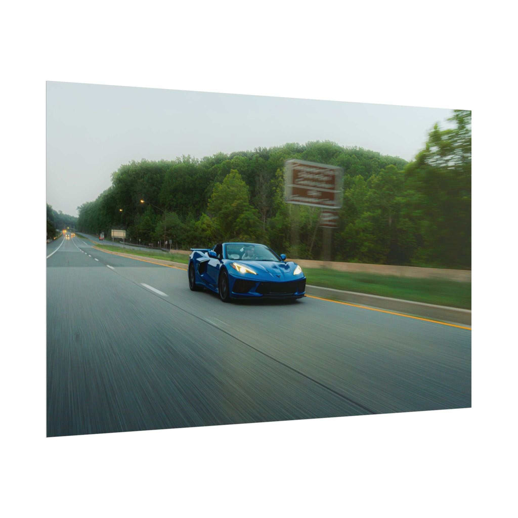 C8 Corvette Stingray blue sports car driving on a paved highway with motion blur and green trees in the background