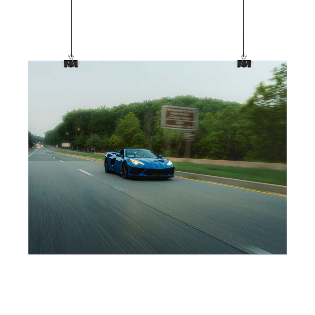 C8 Corvette Stingray blue sports car driving fast on a smooth highway with motion blur and green trees along road