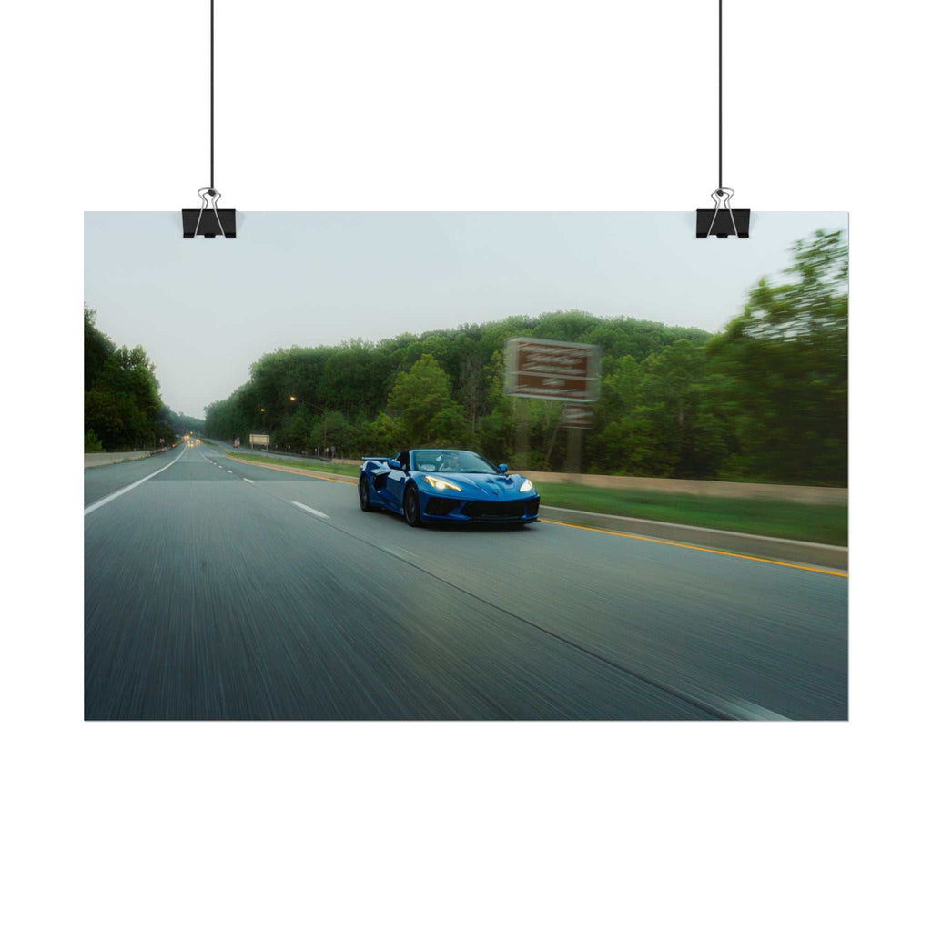C8 Corvette Stingray blue sports car driving fast on a tree-lined highway with motion blur capturing speed