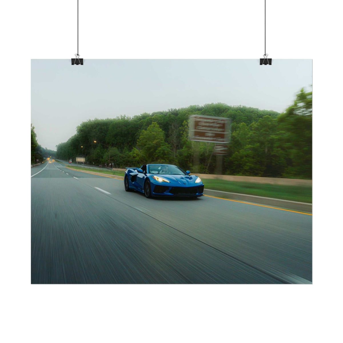 C8 Corvette Stingray blue sports car speeding on a tree-lined highway with motion blur and dynamic depth