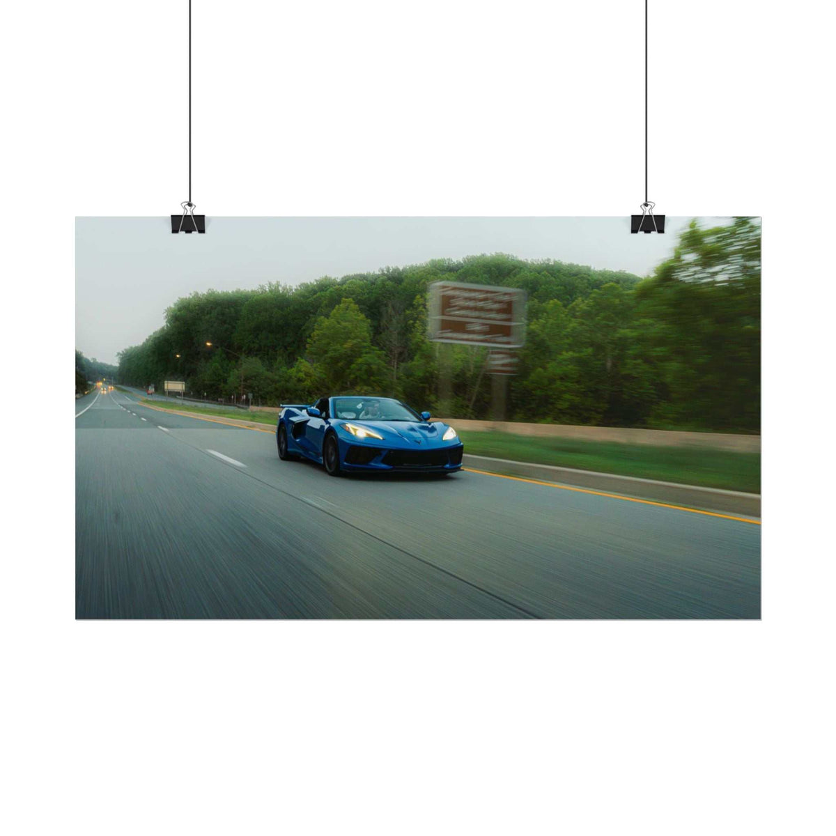C8 Corvette Stingray in deep blue speeding along a tree-lined highway with motion blur and dynamic perspective
