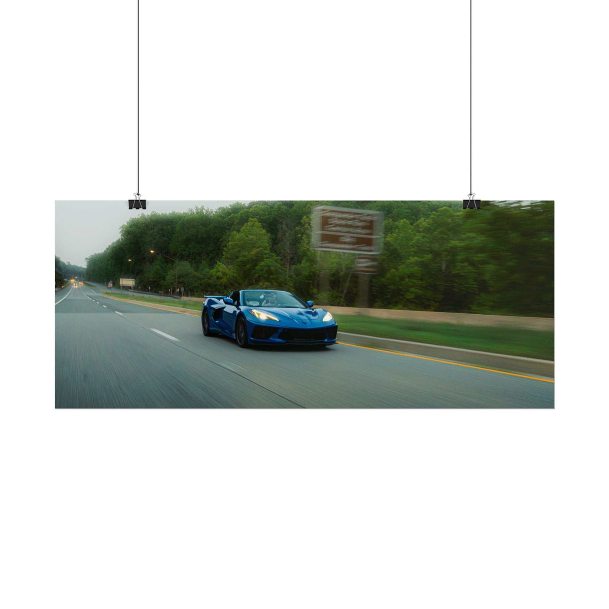 C8 Corvette Stingray blue sports car driving fast on a blurred tree-lined highway capturing motion and speed