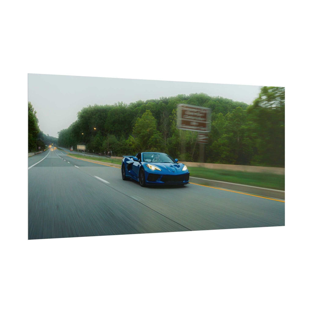 C8 Corvette Stingray blue sports car in motion on a tree-lined highway with blurred road and clear vehicle details