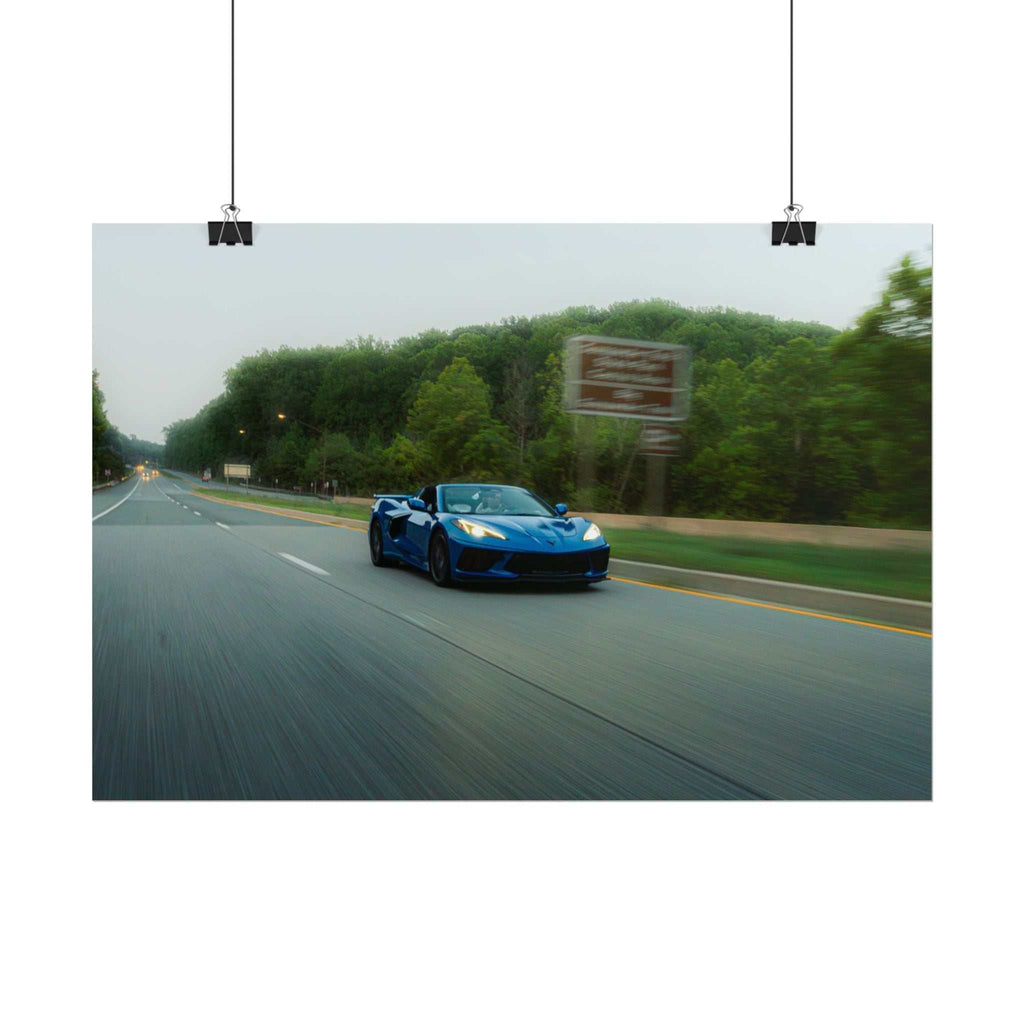 C8 Corvette Stingray in blue driving on a tree-lined highway with motion blur and clear road markings