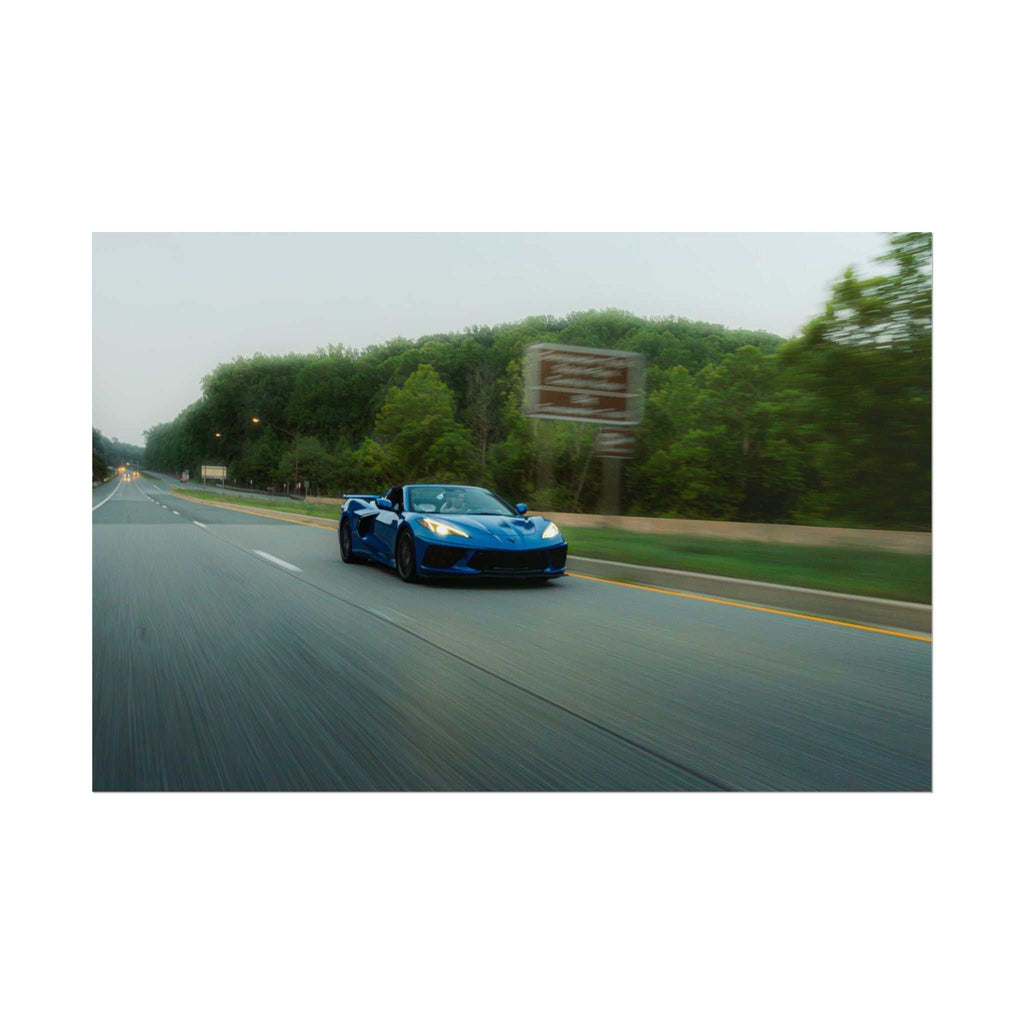 C8 Corvette Stingray blue sports car in motion on a tree-lined highway with speed blur and dynamic motion