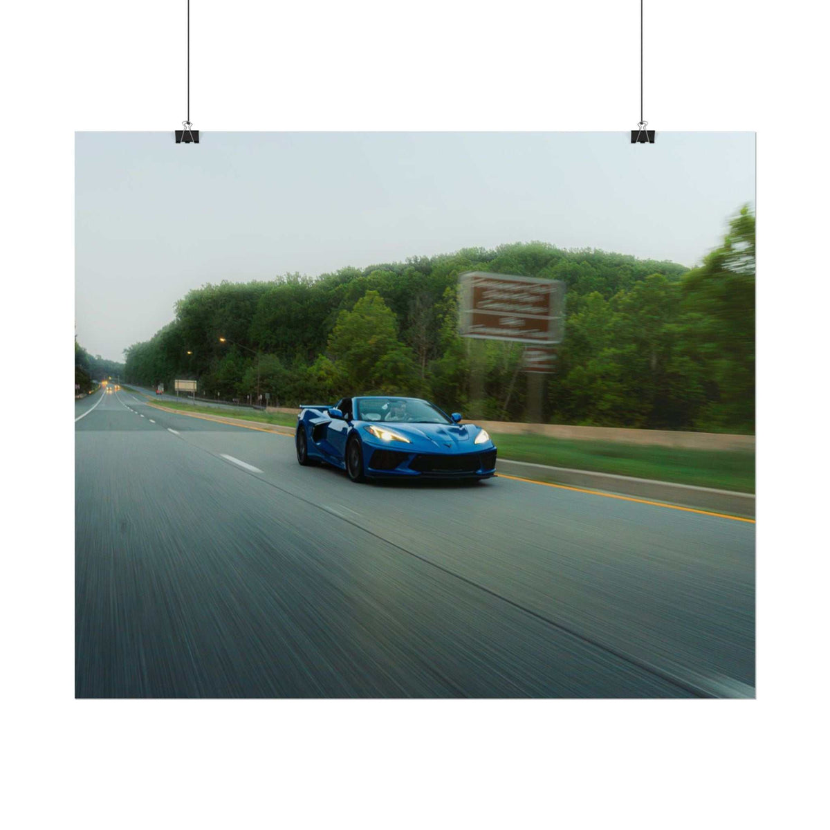 C8 Corvette Stingray blue sports car in motion on a tree-lined highway with speed blur and sharp details