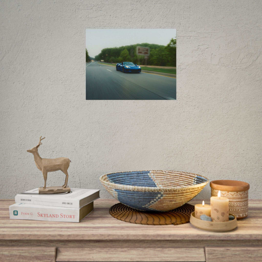 C8 Corvette Stingray blue sports car driving on a tree-lined highway with motion blur capturing speed and depth in a photography poster