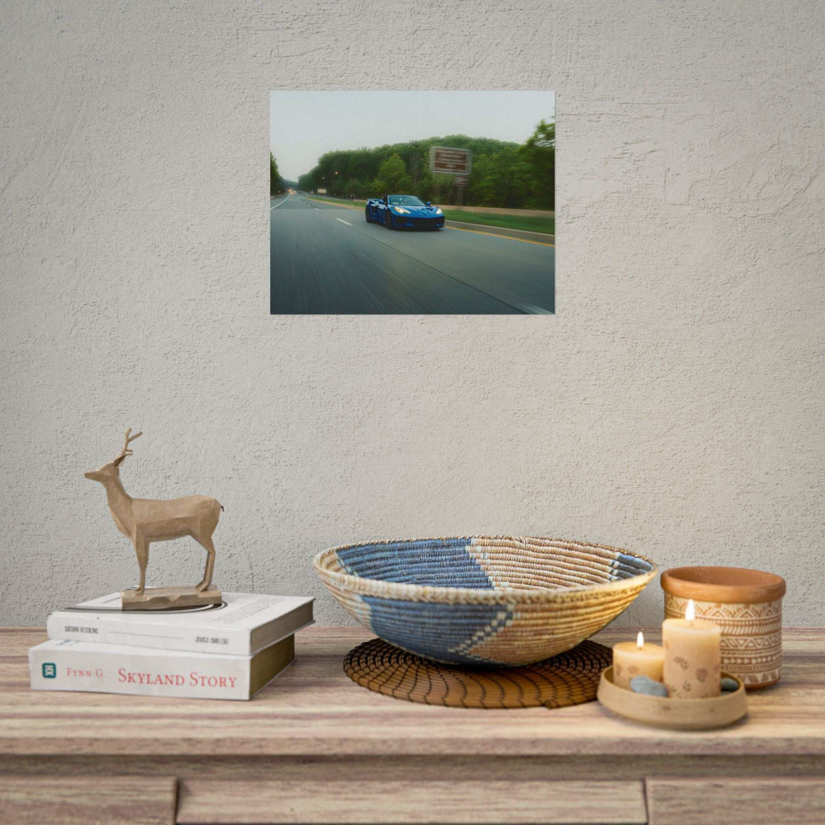 C8 Corvette Stingray blue sports car driving on a tree-lined highway with motion blur capturing speed and depth in a photography poster