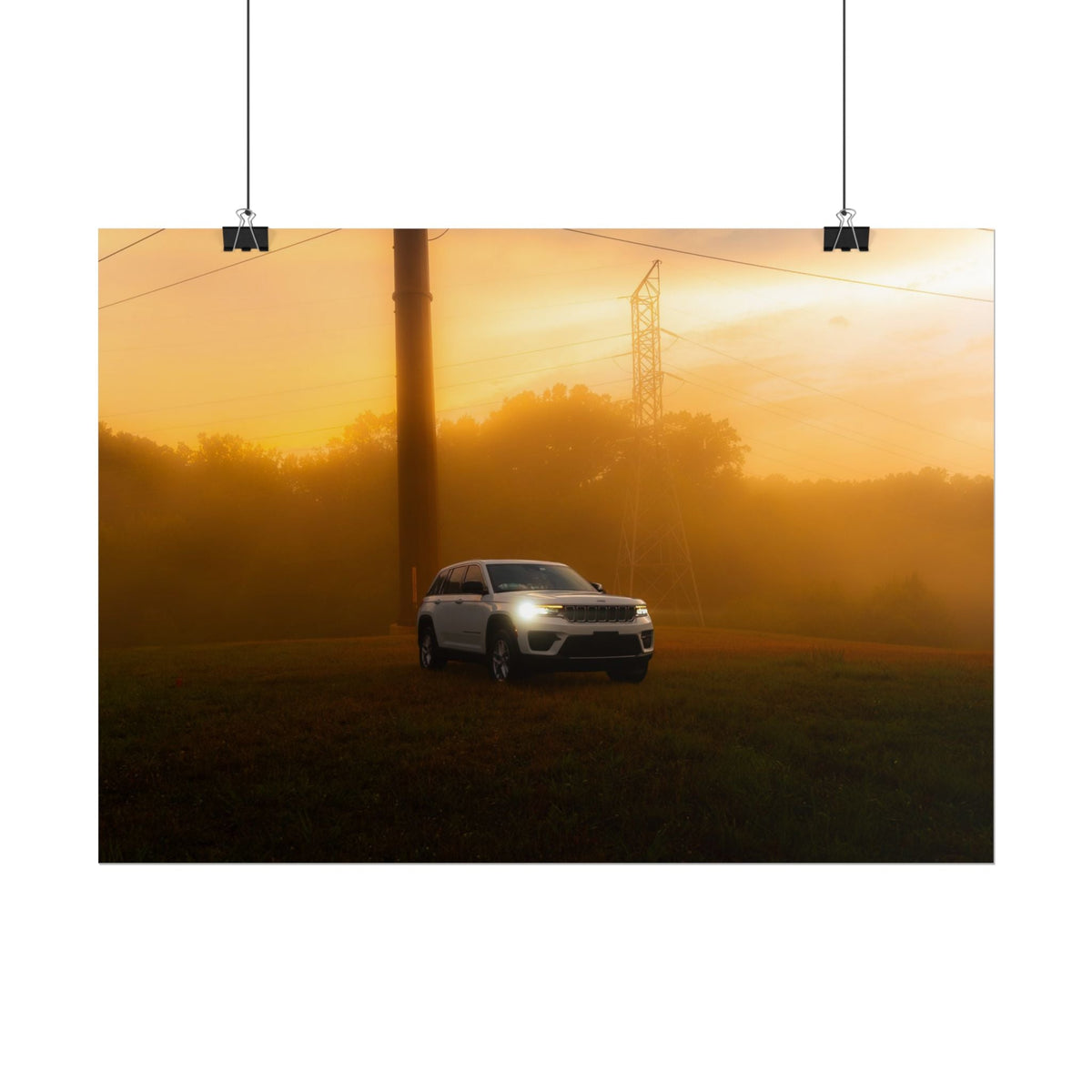 Jeep Grand Cherokee in white cutting through warm amber sunset fog with illuminated headlights and power lines in background