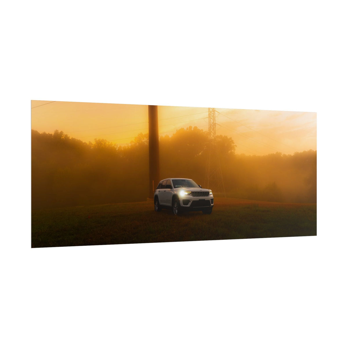 Jeep Grand Cherokee white SUV cutting through warm, hazy amber sunset fog with headlights on and power lines visible