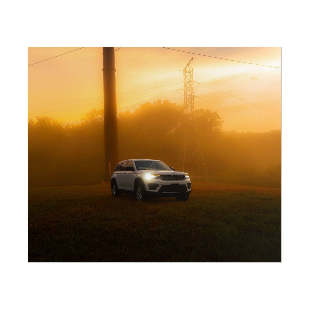 Jeep Grand Cherokee white SUV parked on grassy field with warm sunset fog and power lines in background