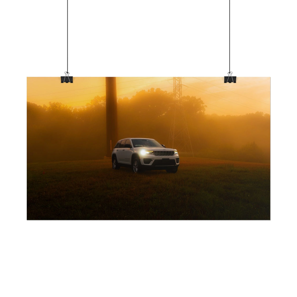 Jeep Grand Cherokee white SUV with headlights on moving through amber sunset fog and mist in a natural landscape