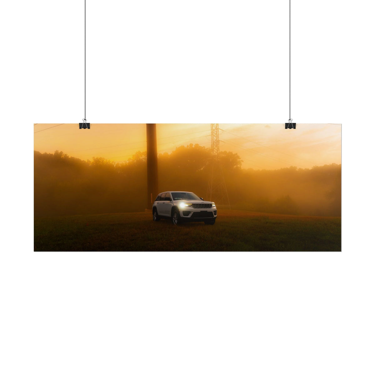 Jeep Grand Cherokee white SUV with headlights on driving through warm orange sunset fog with power lines and trees