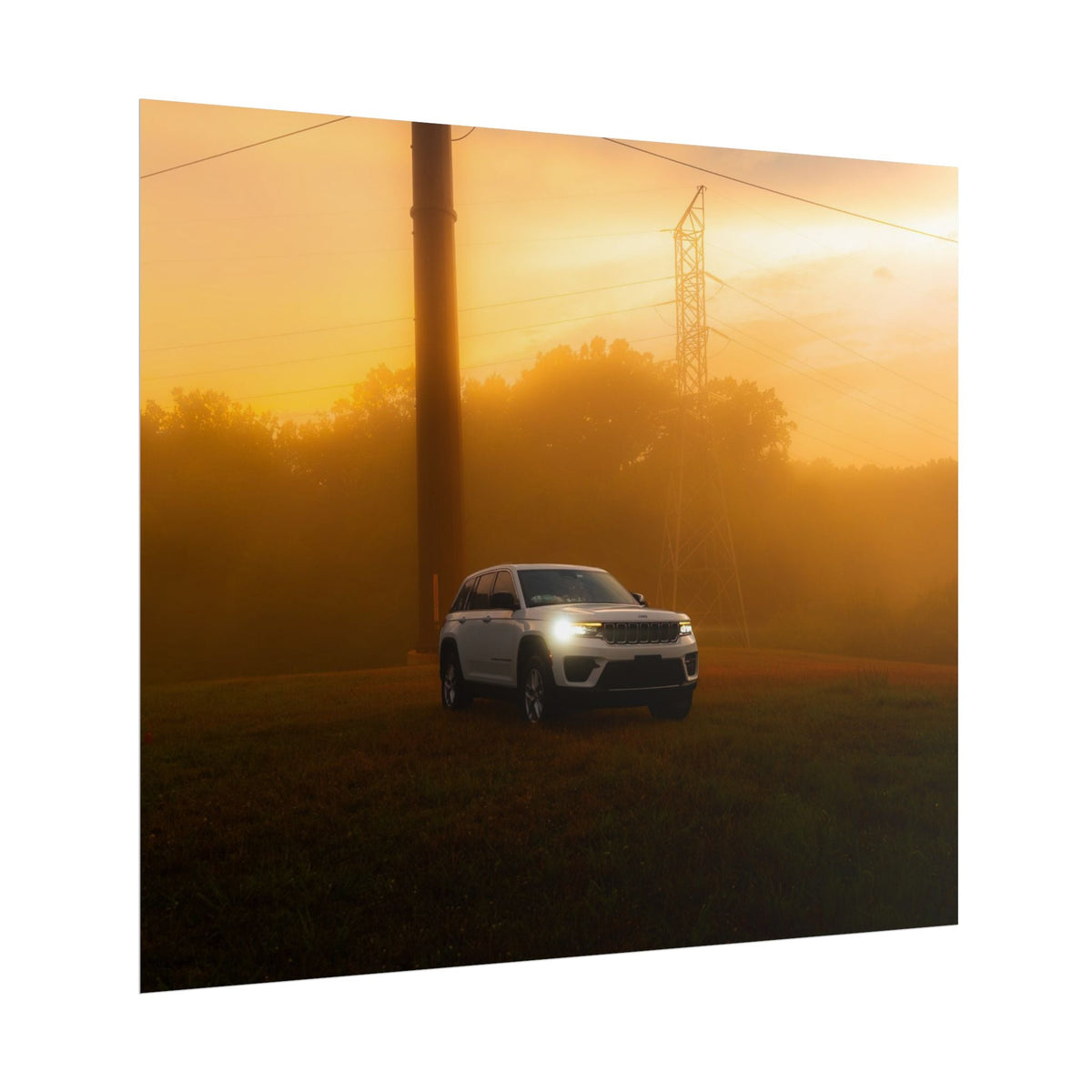 Jeep Grand Cherokee white SUV with headlights on in warm sunset fog landscape featuring power lines and trees in background